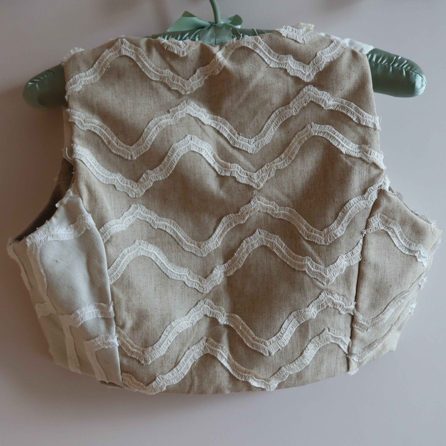 Cropped vest made from up-cycled linen and cotton with vintage lace waves, reversible design for sustainable outerwear fashion.